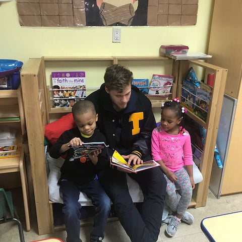 Bailey Flint reading a book to kids at My First Days Daycare