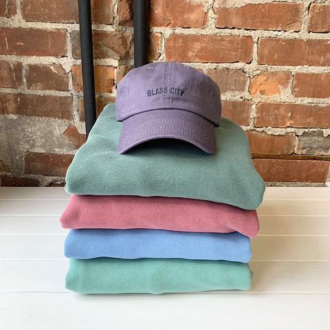 glass city dad hat stacked on embroidered crew sweatshirts
