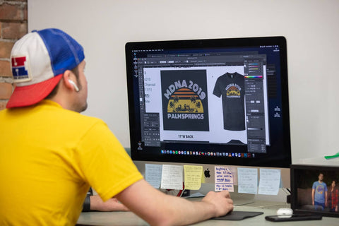 graphic designer creating a design on a computer for screen printing on a t-shirt